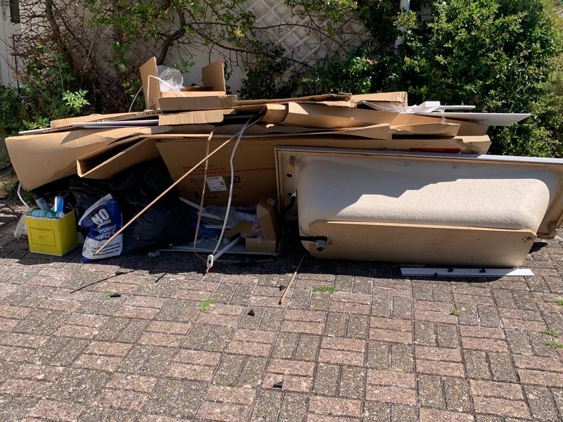 Timber and furniture pieces on a paved area before clearance